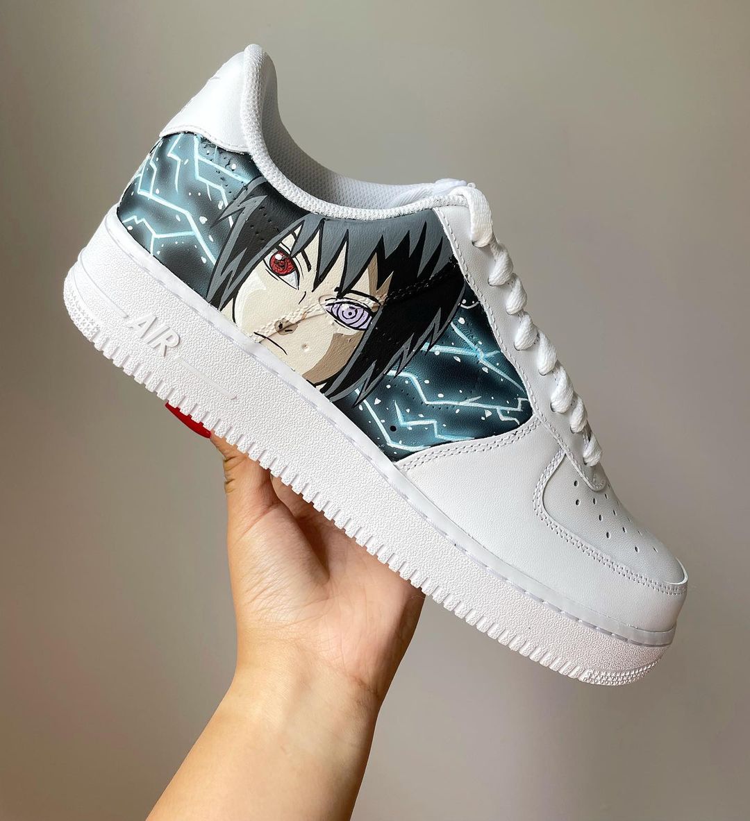 Close-up of a custom sneaker with Sasuke Uchiha’s intense gaze, showing detailed hand-painted anime art on the side panel of a white Nike Air Force 1.