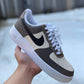 a nike air force 1s sneakers with a beige and brown pastel design on the nike swoosh and sections of the sneakers. Sneakers have a white sole. Snowy background