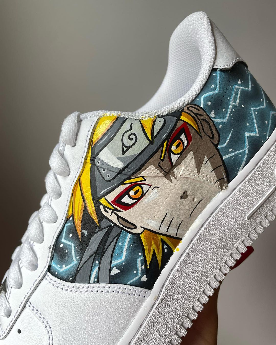 Close-up of a custom sneaker with arutos intense gaze, showing detailed hand-painted anime art on the side panel of a white Nike Air Force 1.