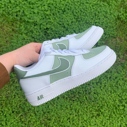 pair of nike air force 1s with a green pastel design on the nike swoosh and front toe panel, green grass background