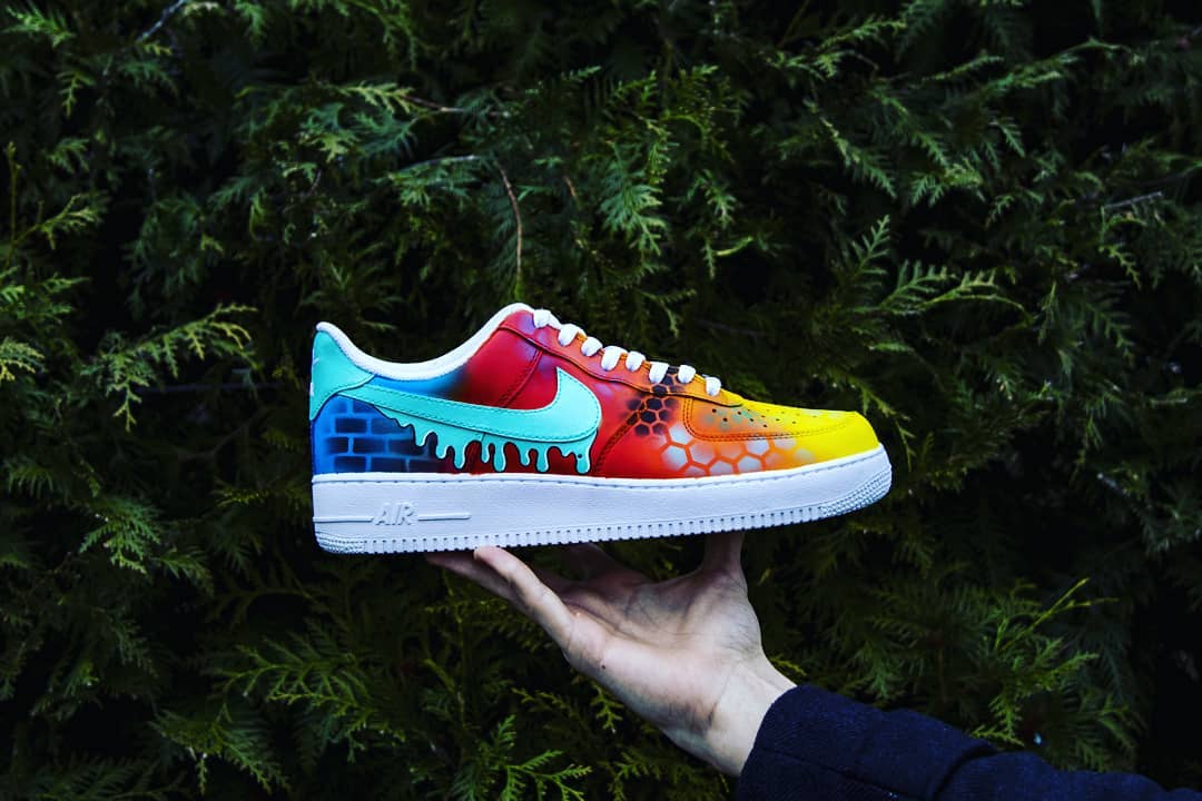 Artistic custom Air Force 1 sneakers with a seamless fade of yellow, orange, red, and blue, complemented by hexed patterns and a dripping swoosh.