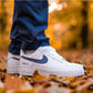 man in blue pants wearing nike air force 1 white sneaker outside, autumn vibe. Nike swoosh is painted navy blue and under the nike swoosh on the side of the sneaker are initials "R&A"