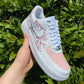 Hand-painted Air Force 1 sneakers featuring a delicate cherry blossom design in pink and white, accented with a soft pink toe cap.
