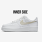 inner side view of white nike air force 1s with a beige swoosh, white background