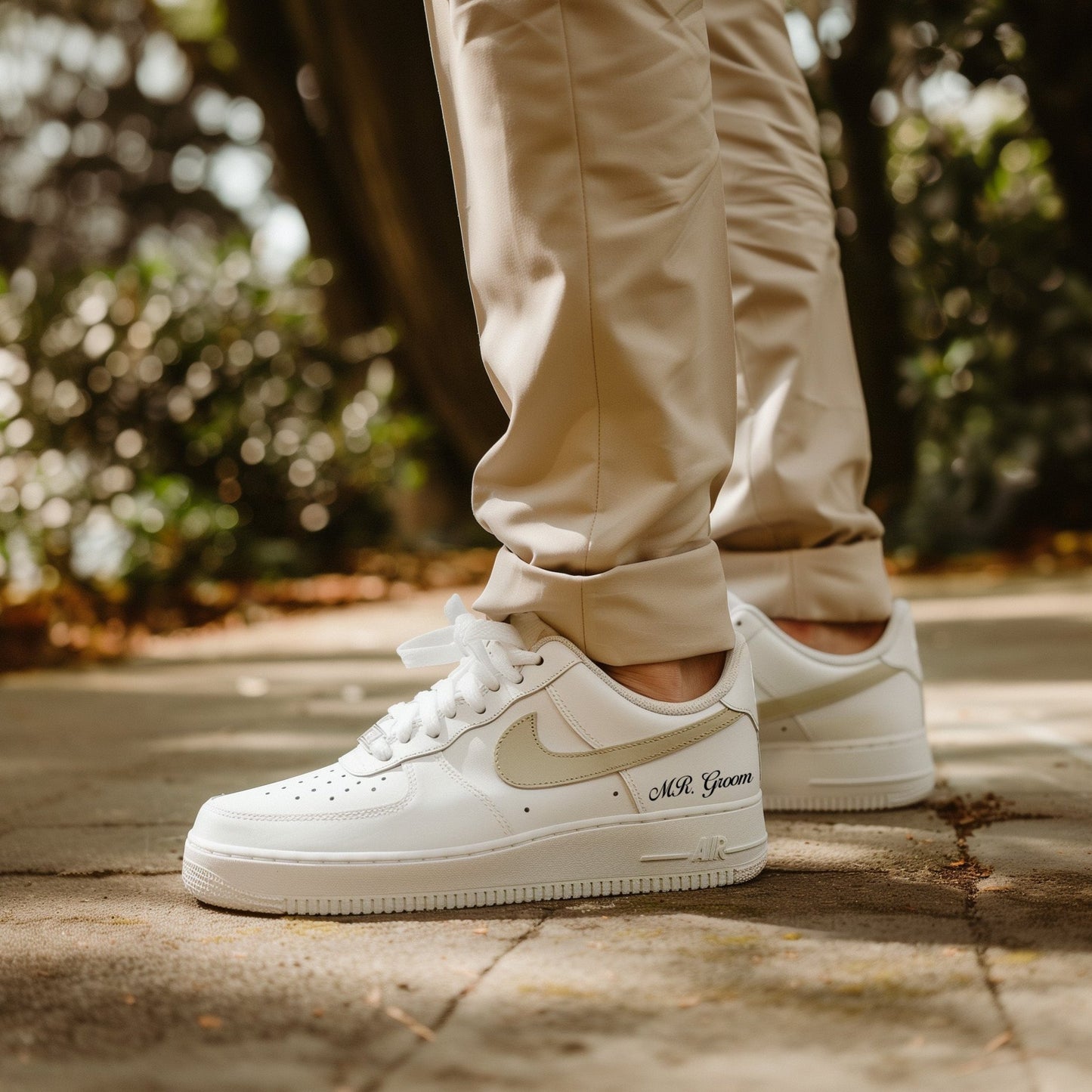 man in beige pants wearing whtie nike air force 1 with a beige swoosh and text mr groom 