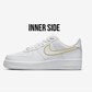 sideview of the inner side of nike air force 1 low white model, nike swoosh is custom handpainted with a gold outline