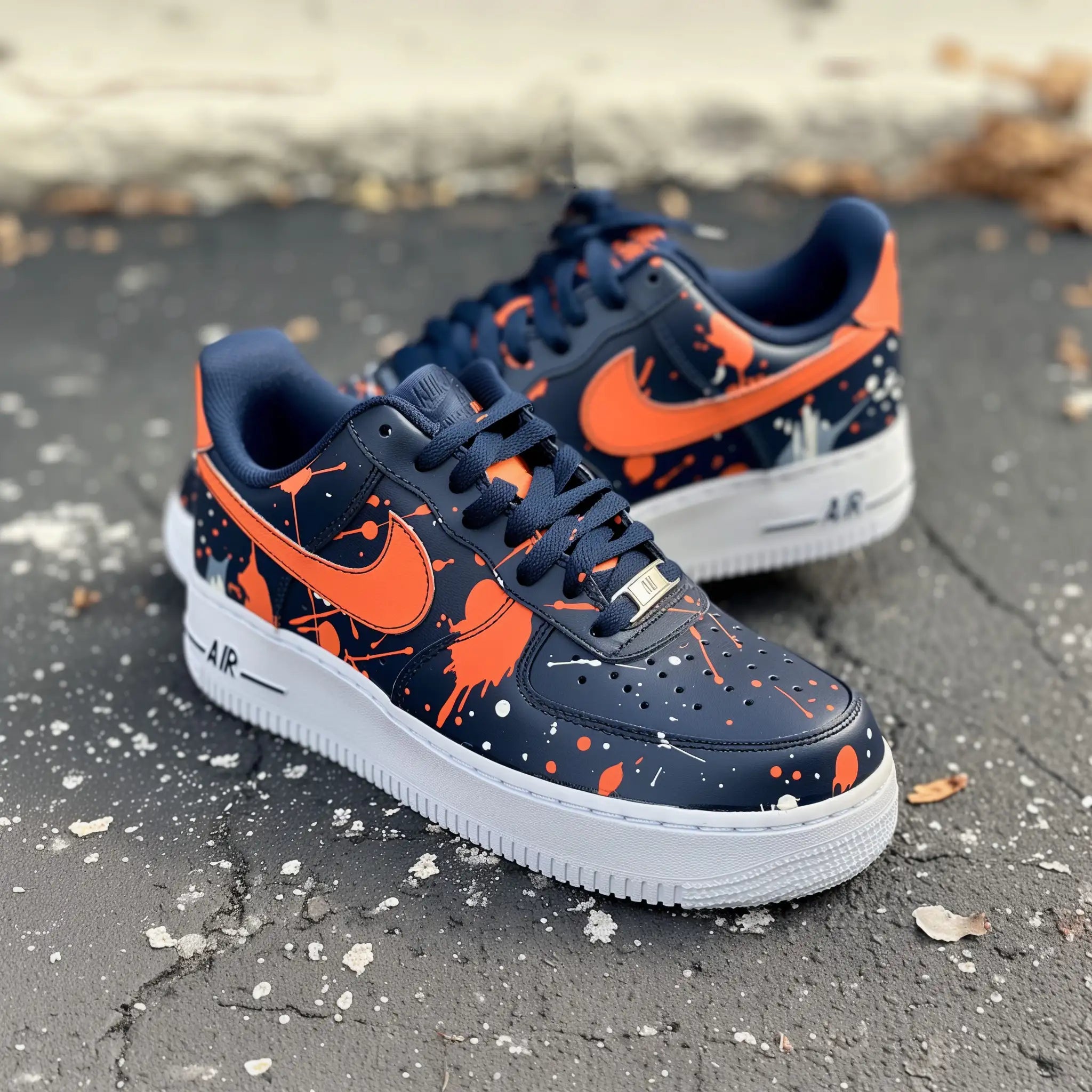 white nike air force 1s covered in navy blue with orange nike logos and orange paint splatter all over the sneakers. Sneakers have  a white sole and navy blue shoelaces. Design is on all sides. 