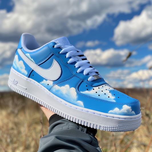 nike air force 1 with handpainted cloud designs, sneaker is covered in blue except for the white sole. on the blue base are painted white clouds. 
