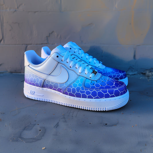 white nike air force 1s with a blue fade hexed design. sneakers have a blue fade from the bottom fading into white as the desing goes higher. on the blue parts are handpainted hexed patterns in white. street background
