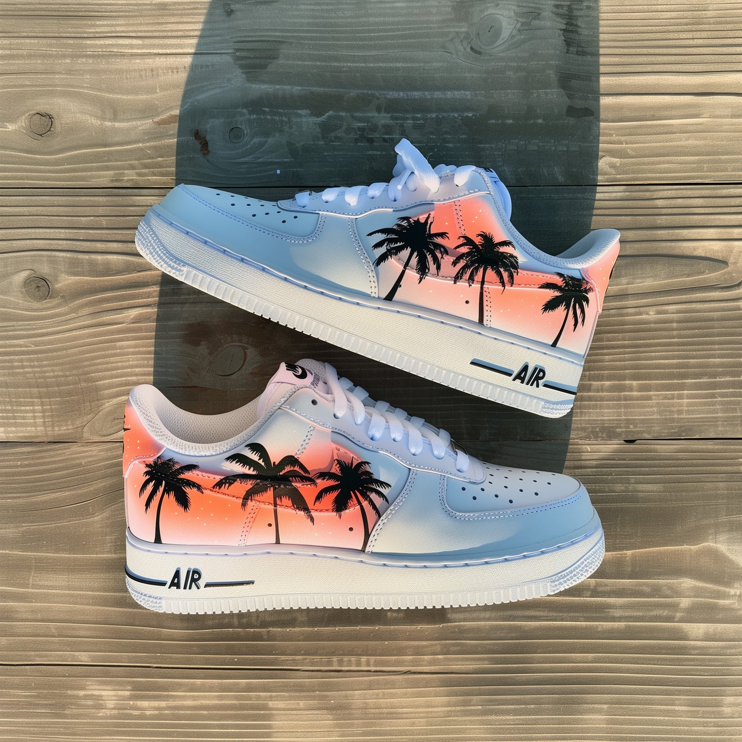 white nike air force 1s with palm trees painted in black on the sides of the sneakers, under the palm trees is a pinkish orange fade. sole stripe on the white soles is painted in black 