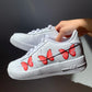a pair of nike air force 1s with a simple red butterfly design on the outside sections of the sneakers. Blank gray shadow wall on the background