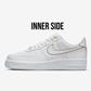 Inner side of white nike air force 1s, nike logo is outlined in gold