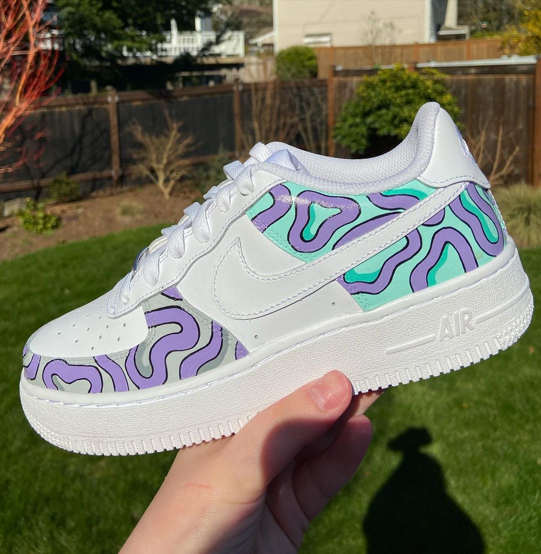 Hand-painted Nike Air Force 1 sneakers featuring vibrant lavender and mint patterns, with swirling lines that create a bold, custom design for sneaker enthusiasts