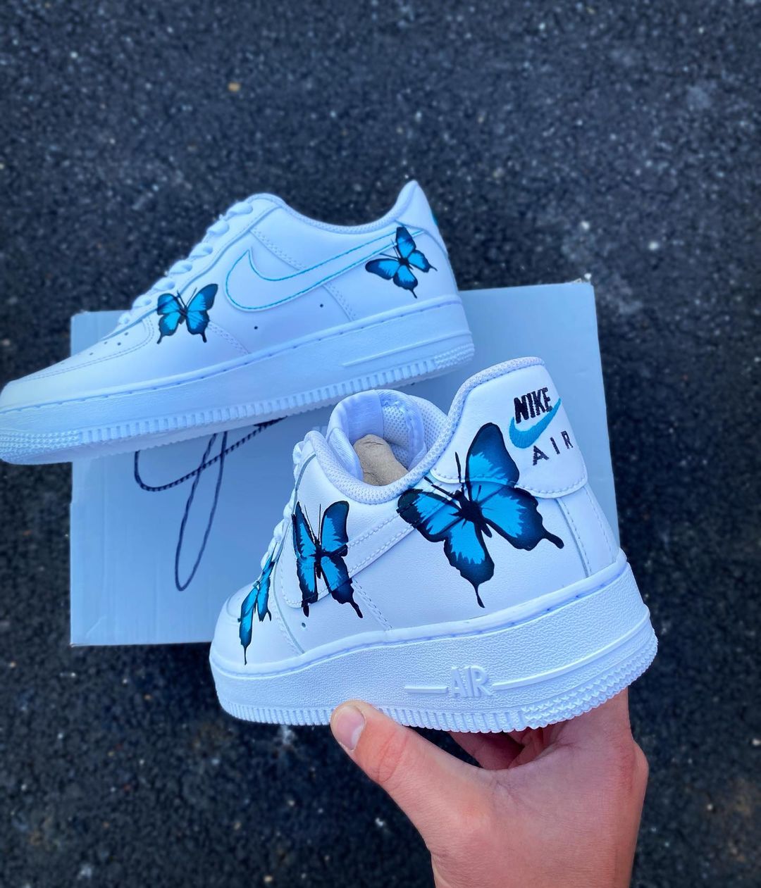 Custom Nike Air Force 1 sneakers with handpainted blue butterfly designs, adding a vibrant touch to the white base.