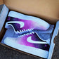 Pair of custom Nike Air Force 1 sneakers in a shoebox, showcasing a purple-to-black galaxy fade with white swoosh.