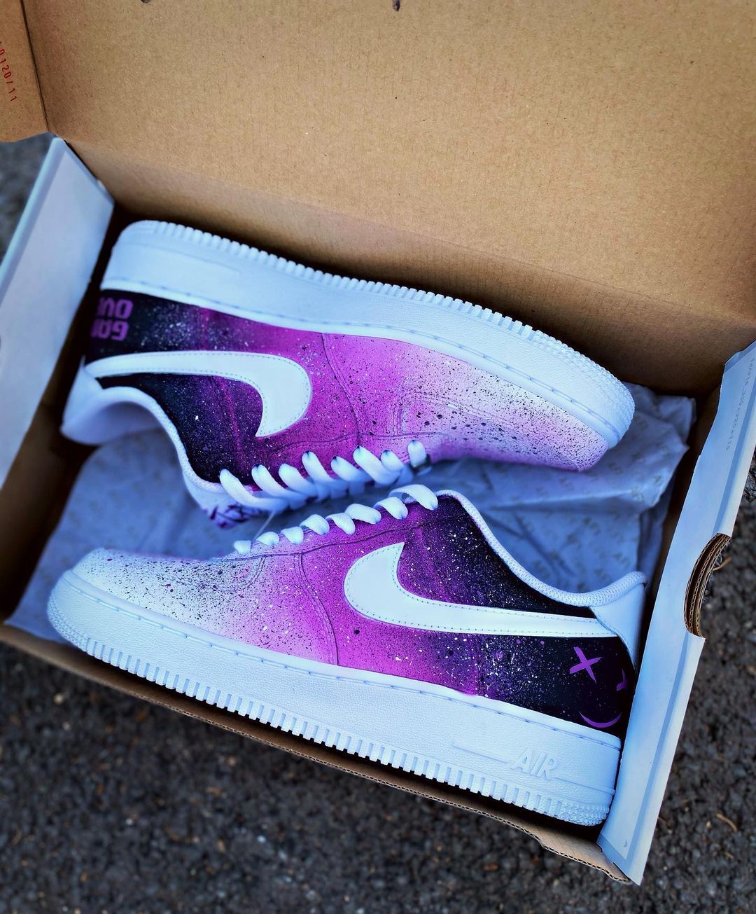 Pair of custom Nike Air Force 1 sneakers in a shoebox, showcasing a purple-to-black galaxy fade with white swoosh.