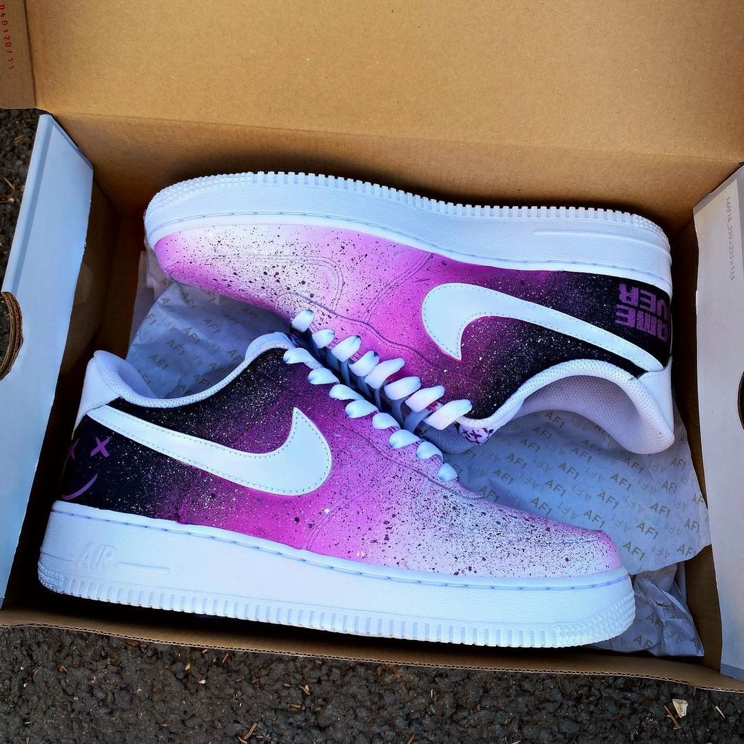 Pair of custom Nike Air Force 1 sneakers in a shoebox, showcasing a vibrant purple-to-black galaxy fade with white swoosh.