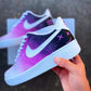 Close-up of custom Nike Air Force 1 shoe, handpainted in a purple and black galaxy style with smiley face details on the heel.