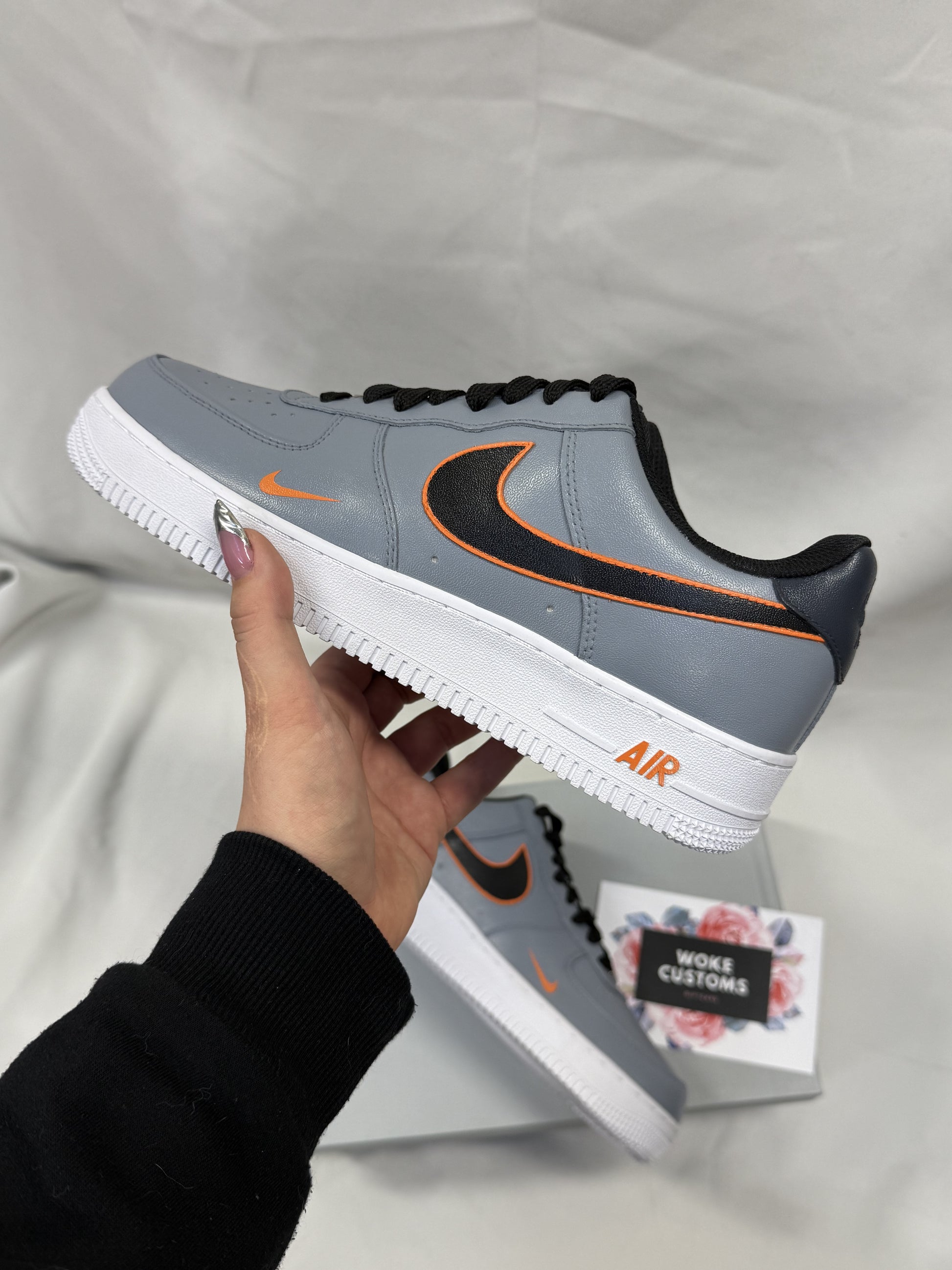 Close-up of custom Nike Air Force 1 sneakers featuring a bold gray-and-orange outline effect on a sleek leather base