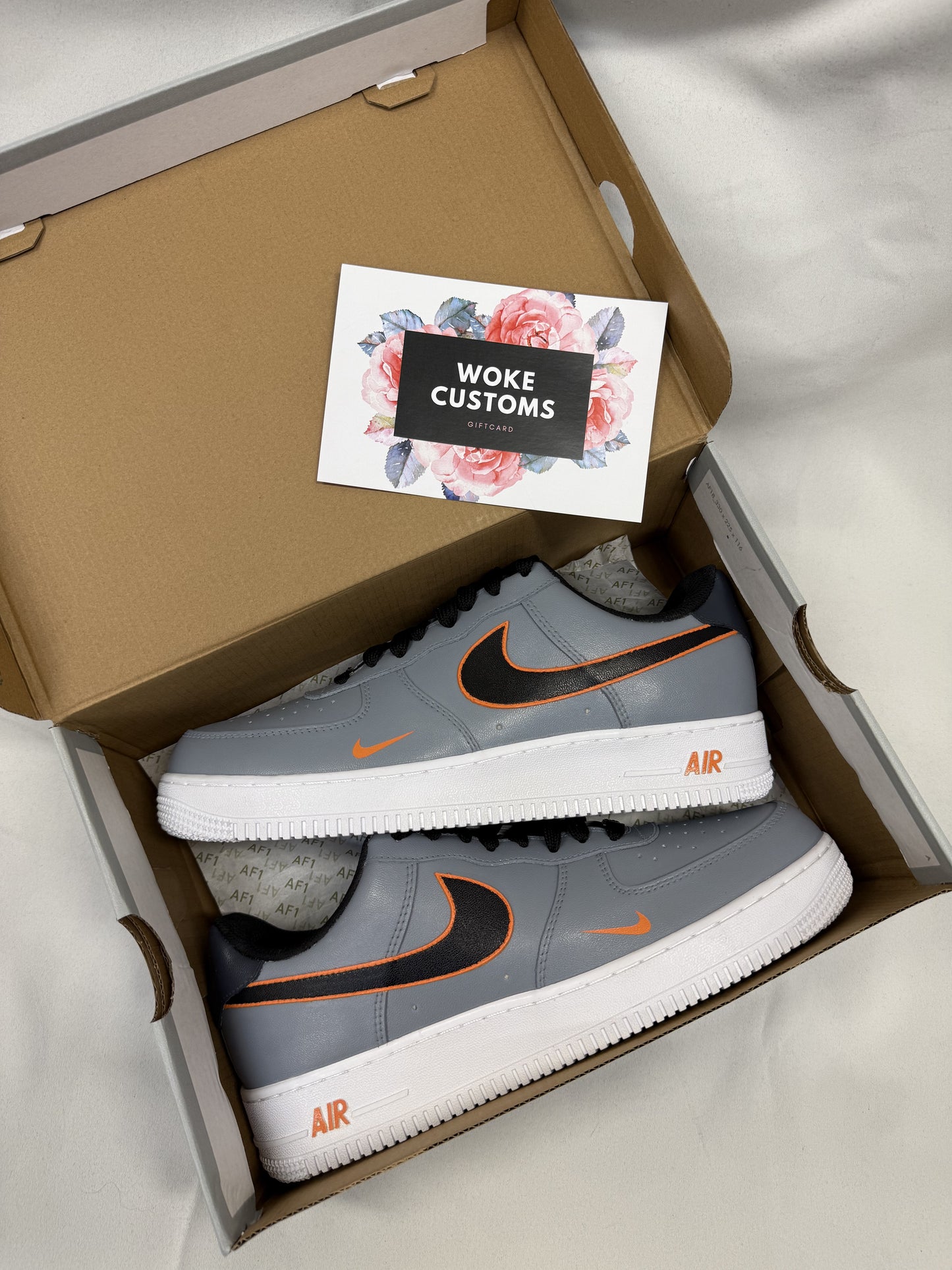 Close-up of custom Nike Air Force 1 sneakers featuring a bold gray-and-orange outline effect on a sleek leather base