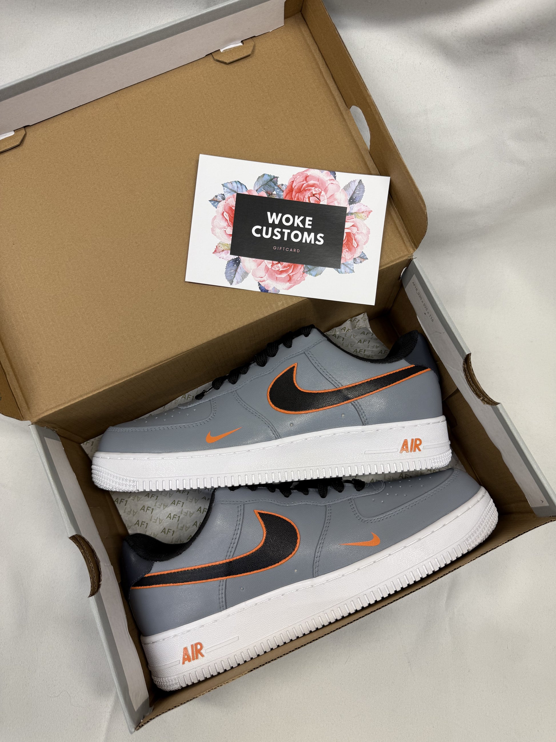 Close-up of custom Nike Air Force 1 sneakers featuring a bold gray-and-orange outline effect on a sleek leather base