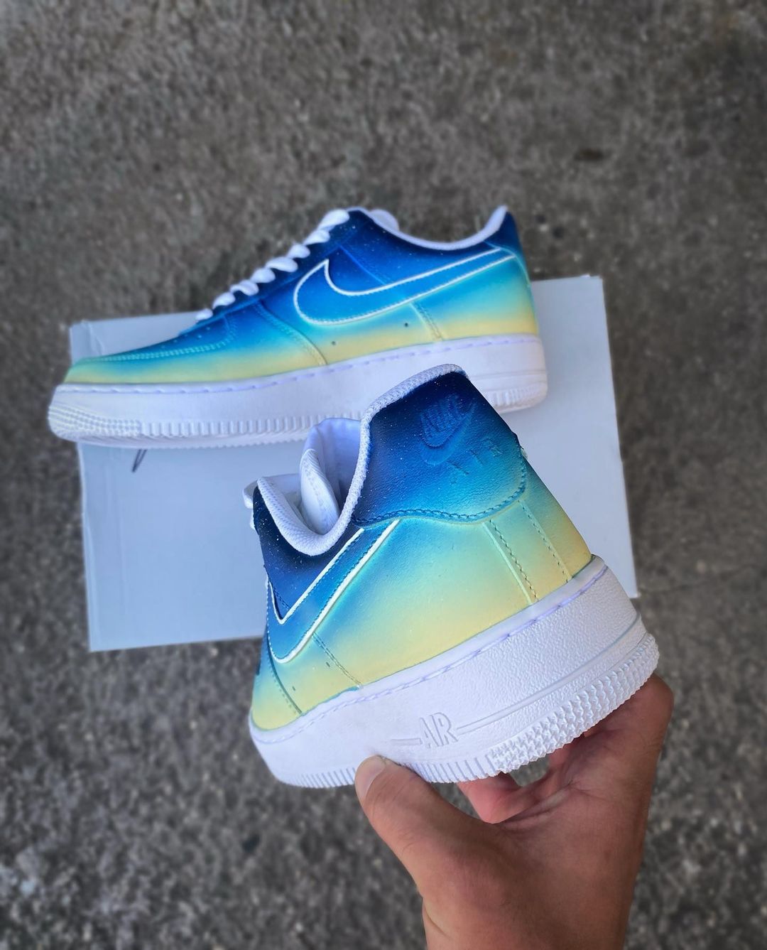 Pair of custom Nike Air Force 1 shoes showcasing a seamless blue and yellow gradient, with clean white accents.