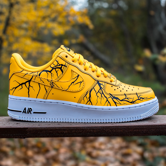 Close-up of custom Nike Air Force 1 sneakers featuring a black lightning bolt pattern on a vibrant yellow background.