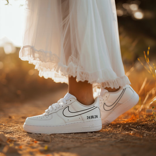 woman in white dress wearing white nike air force 1 sneaker with a nike logo outline in black and a date on the outside of the sneaker