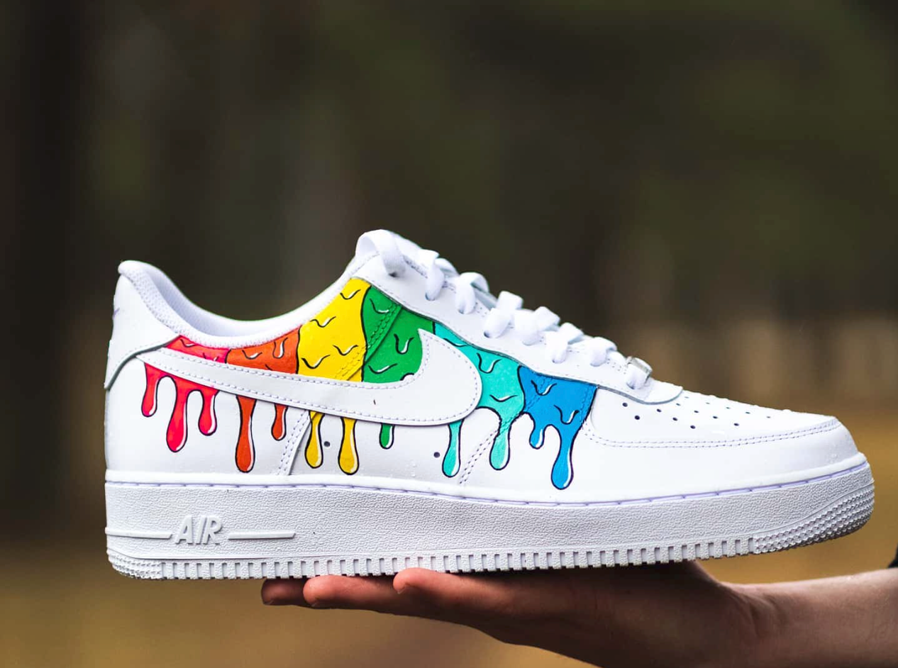 a single custom nike air force 1 white sneaker placed on a hand with colorful paint dripping design on the side of the sneaker