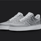 The image is featuring a Custom gray cartoon Air force 1 sneaker pair on a blank black background. The white nike sneakers have a gray cartoon design on the entire air force sneakers. 