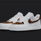 The image is of a Custom Nike Air force 1 sneaker pair on a blank black background. The white custom sneakers have a Cheetah print in the front and on the nike logos. 