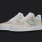 The image is of a Custom Nike Air force 1 sneaker pair on a blank black background. The white custom sneakers have a creme tone and the nike logo is in a mint colorway. 
