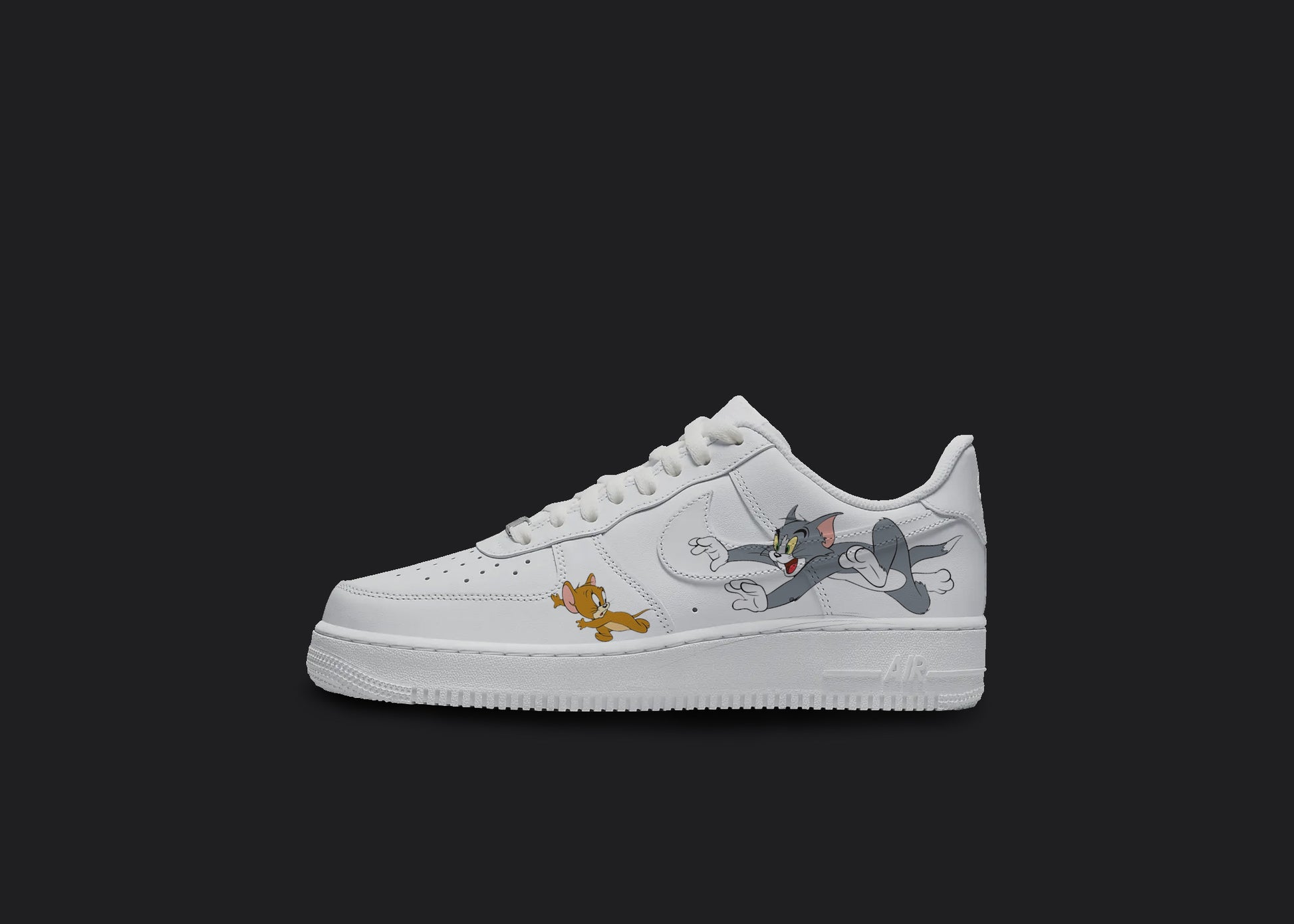  The image is of a Custom Nike Air force 1 shoes on a blank black background. The white custom nike shoe has a tom and jerry design on the side.  