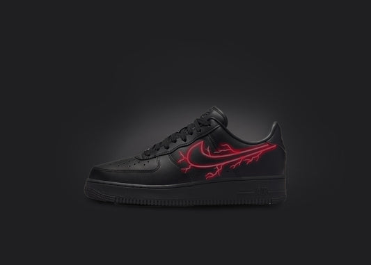 The image is featuring a custom black Air force 1 sneaker on a blank black background. The black nike sneaker has a red lightning design on the nike logo. 