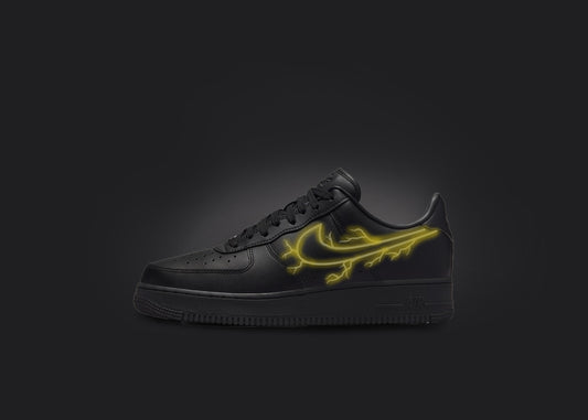 The image is featuring a custom black Air force 1 sneaker on a blank black background. The black nike sneaker has a yellow lightning design on the nike logo. 