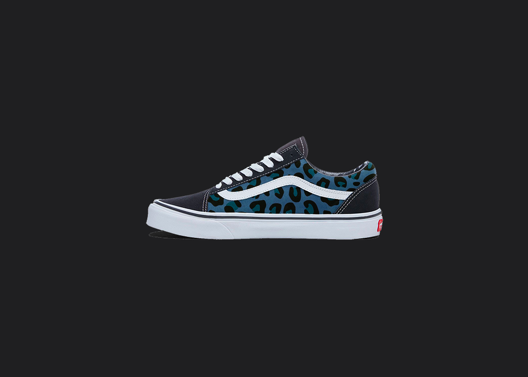 The image is featuring a custom hand painted cheetah print vans shoes on a blank black background. The vans old skools sneaker has a blue cheetah print design on the side of shoes. 