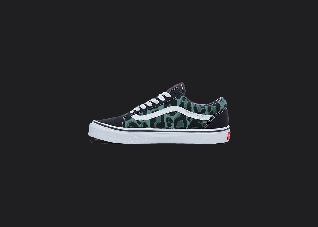 The image is featuring a custom hand painted leopard print vans shoes on a blank black background. The vans old skools sneaker has a Blue leopard print design on the side of shoes. 