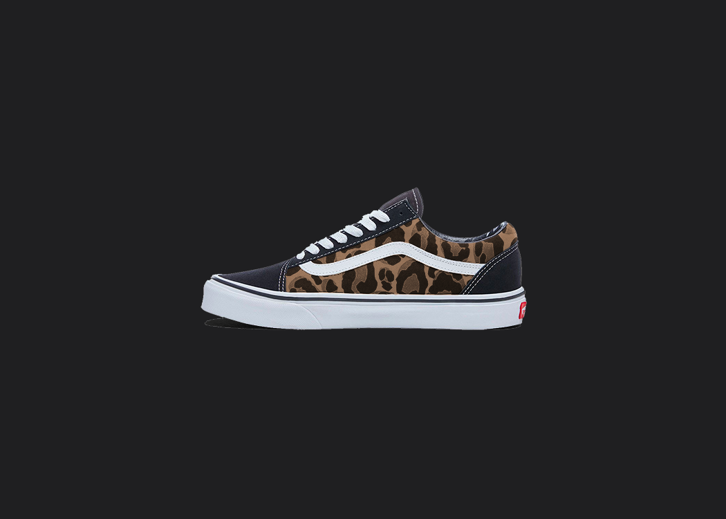 The image is featuring a custom hand painted leopard print vans shoes on a blank black background. The vans old skools sneaker has a leopard print design on the side of shoes. 