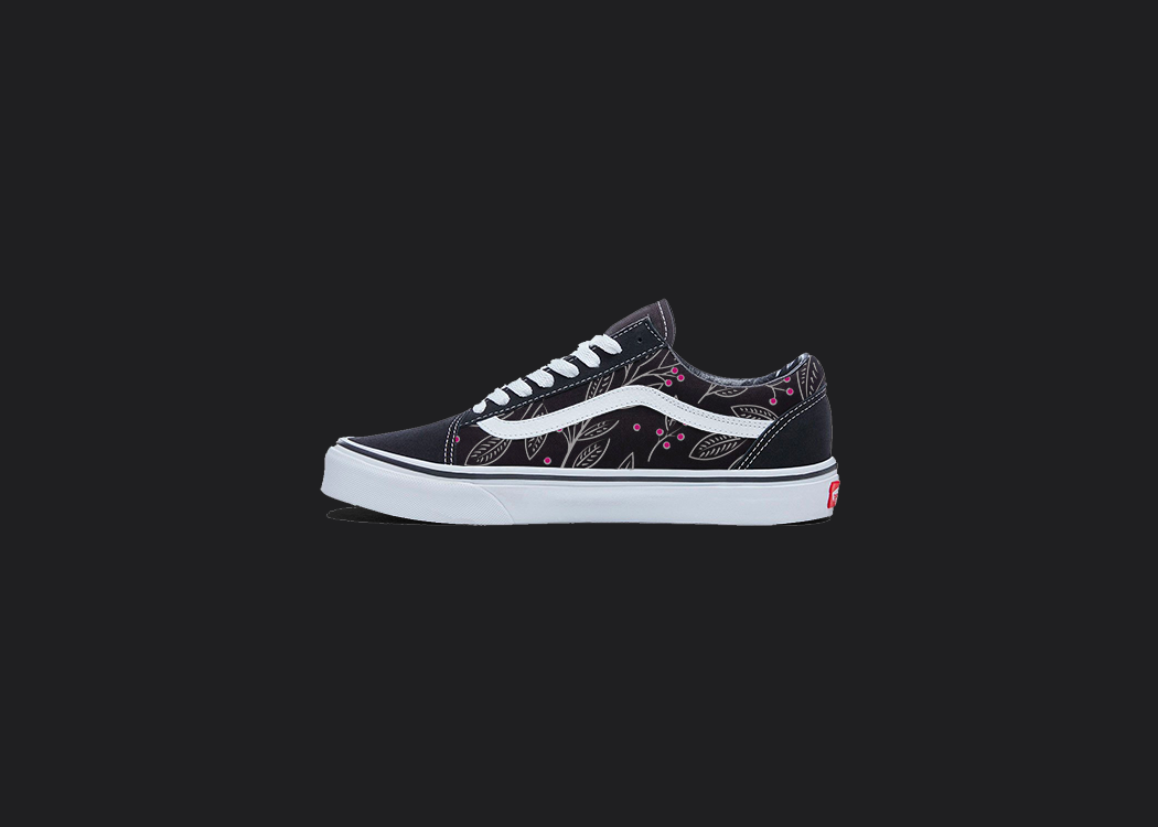 The image is featuring a custom hand painted floral shoes on a blank black background. The vans old skools sneaker has a pink floral print design on the side of shoes. 