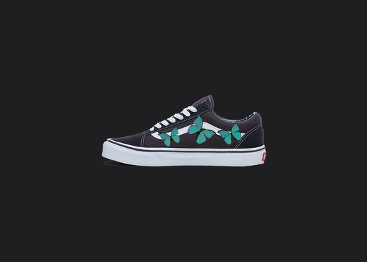 The image is featuring a custom hand painted vans shoes on a blank black background. The vans old skools sneaker has a custom pastel Butterfly design on the side of shoes. 