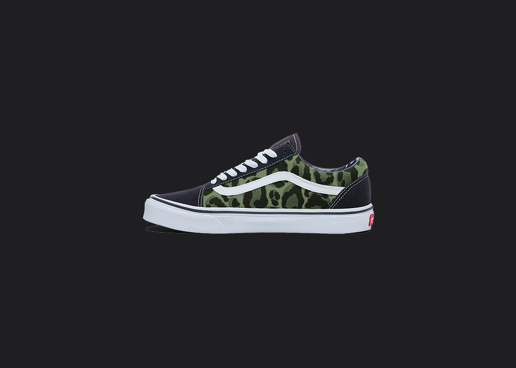 The image is featuring a custom hand painted leopard print vans shoes on a blank black background. The vans old skools sneaker has a green leopard print design on the side of shoes. 
