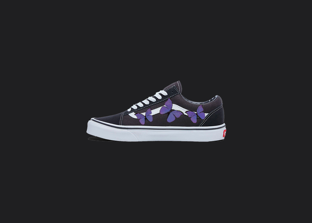The image is featuring a custom hand painted vans shoes on a blank black background. The vans old skools sneaker has a custom purple Butterfly design on the side of shoes. 