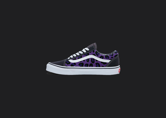 The image is featuring a custom hand painted cheetah print vans shoes on a blank black background. The vans old skools sneaker has a purple cheetah print design on the side of shoes.