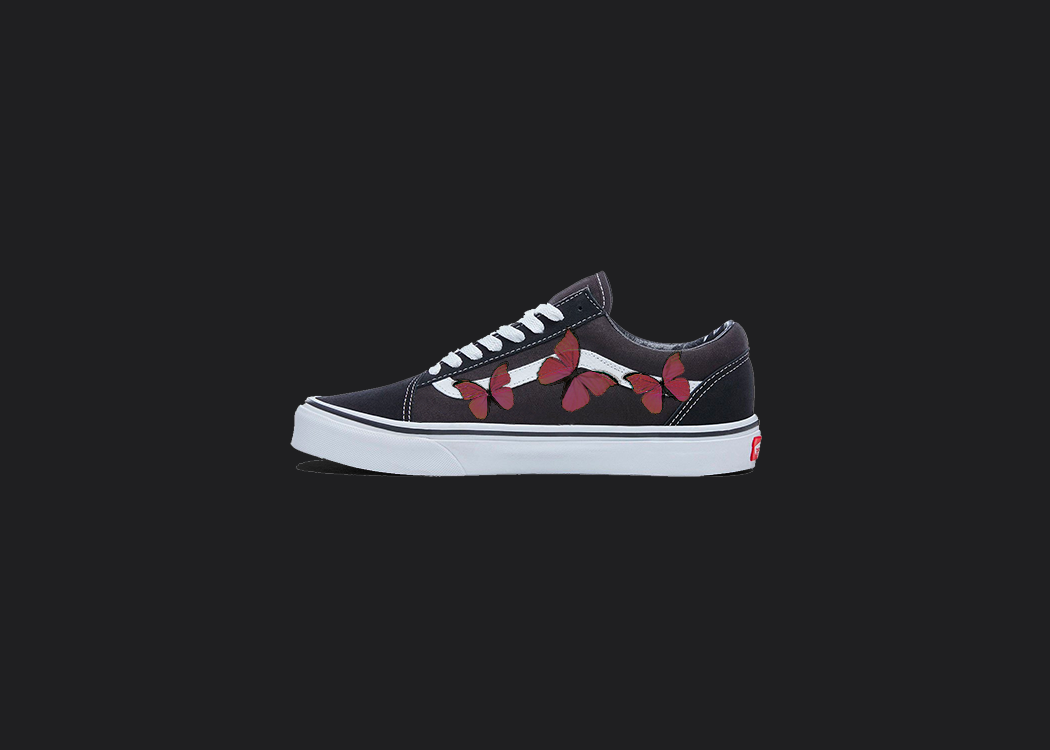 The image is featuring a custom hand painted vans shoes on a blank black background. The vans old skools sneaker has a custom red Butterfly design on the side of shoes. 