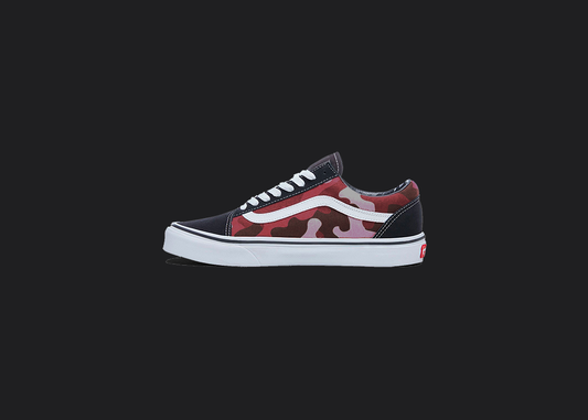 The image is featuring a custom hand painted vans shoes on a blank black background. The vans old skools sneaker has a custom red camo design on the side of shoes. 