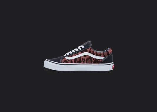 The image is featuring a custom hand painted leopard print vans shoes on a blank black background. The vans old skools sneaker has a red leopard print design on the side of shoes. 