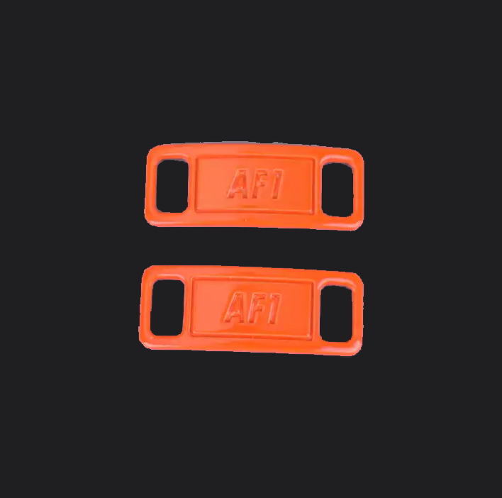 The image is featuring a pair of orange shoe tags on a blank black background. The air force 1 shoes tags are for sneaker laces and come in pairs. 